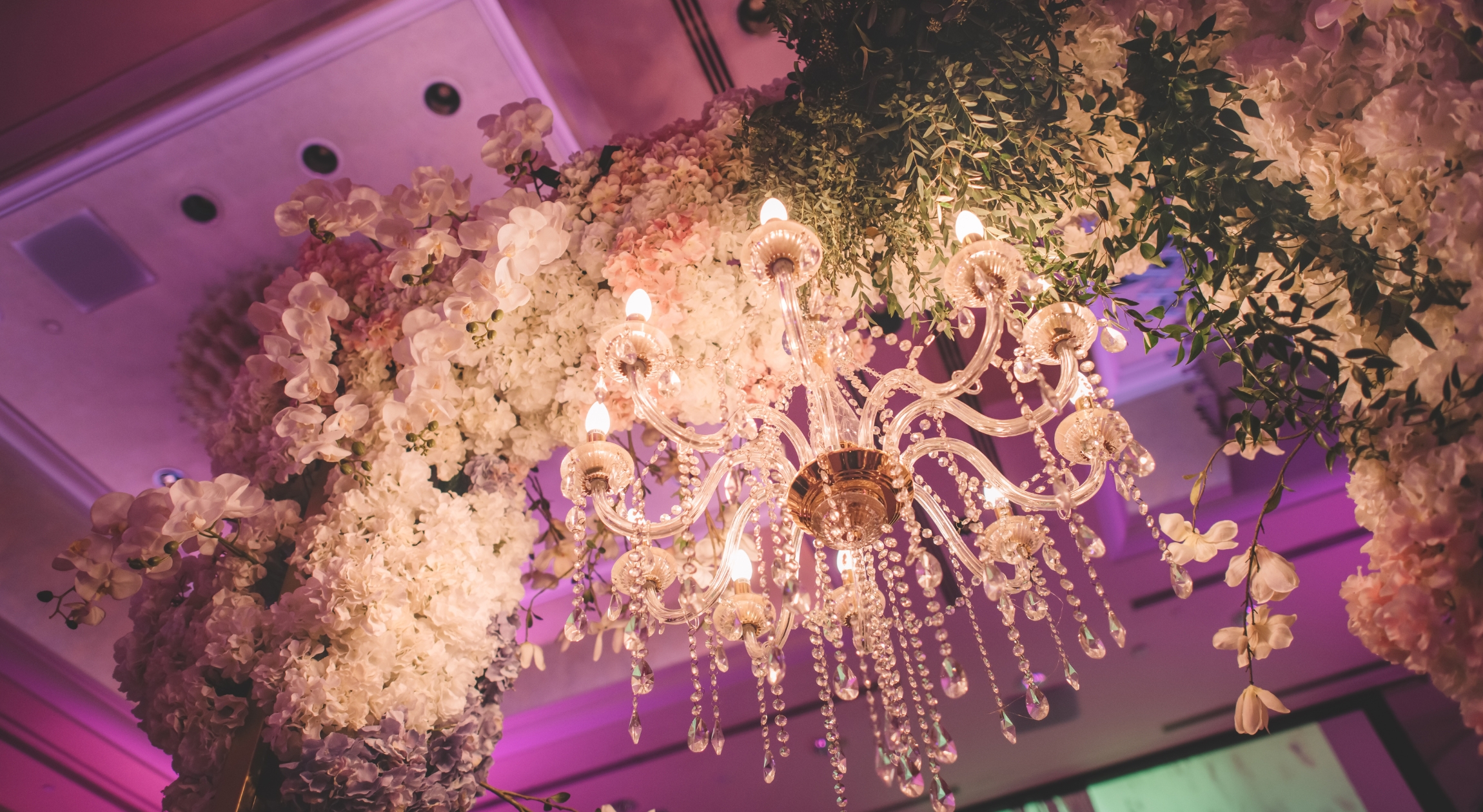 A chandelier handing on an installation with a lot of flowers