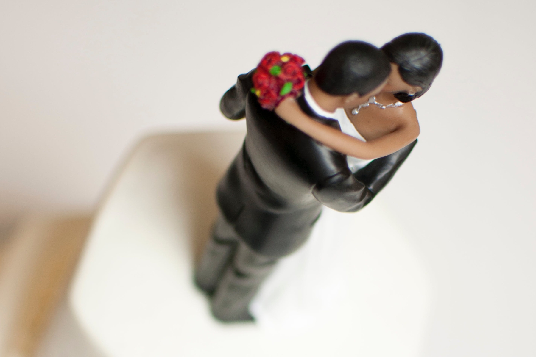 A Black groom and bride figurine are on top of a white cake