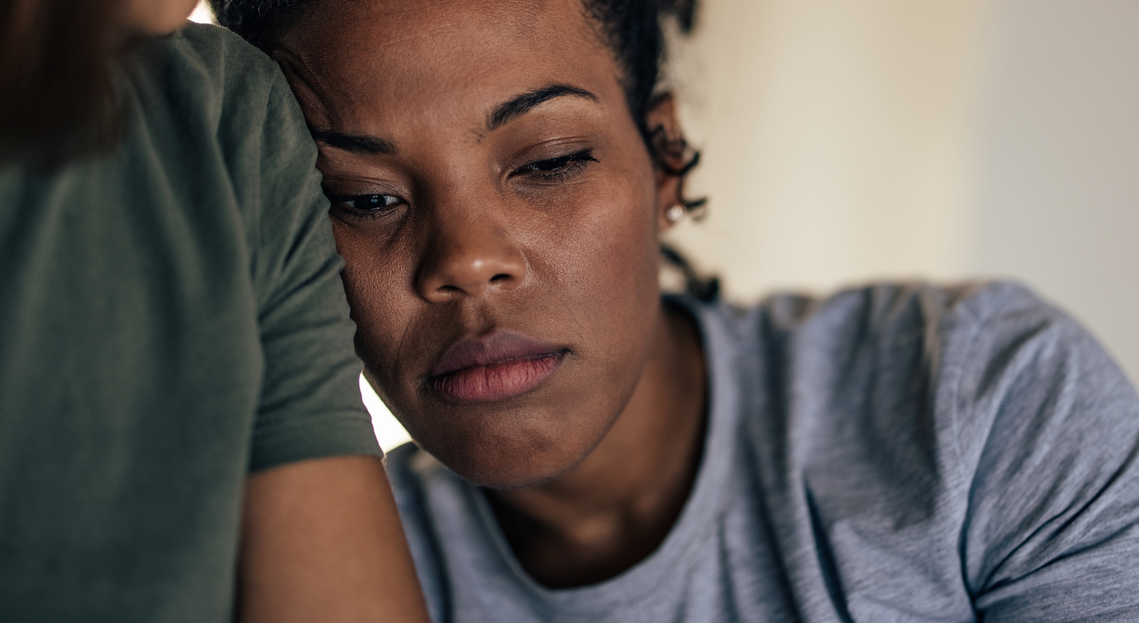 A sad African American woman leaning on the shoulder of someone