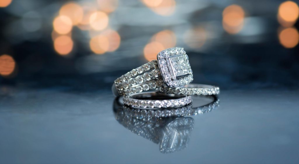 A set of jewelry that includes an engagement ring with many diamonds and two bands