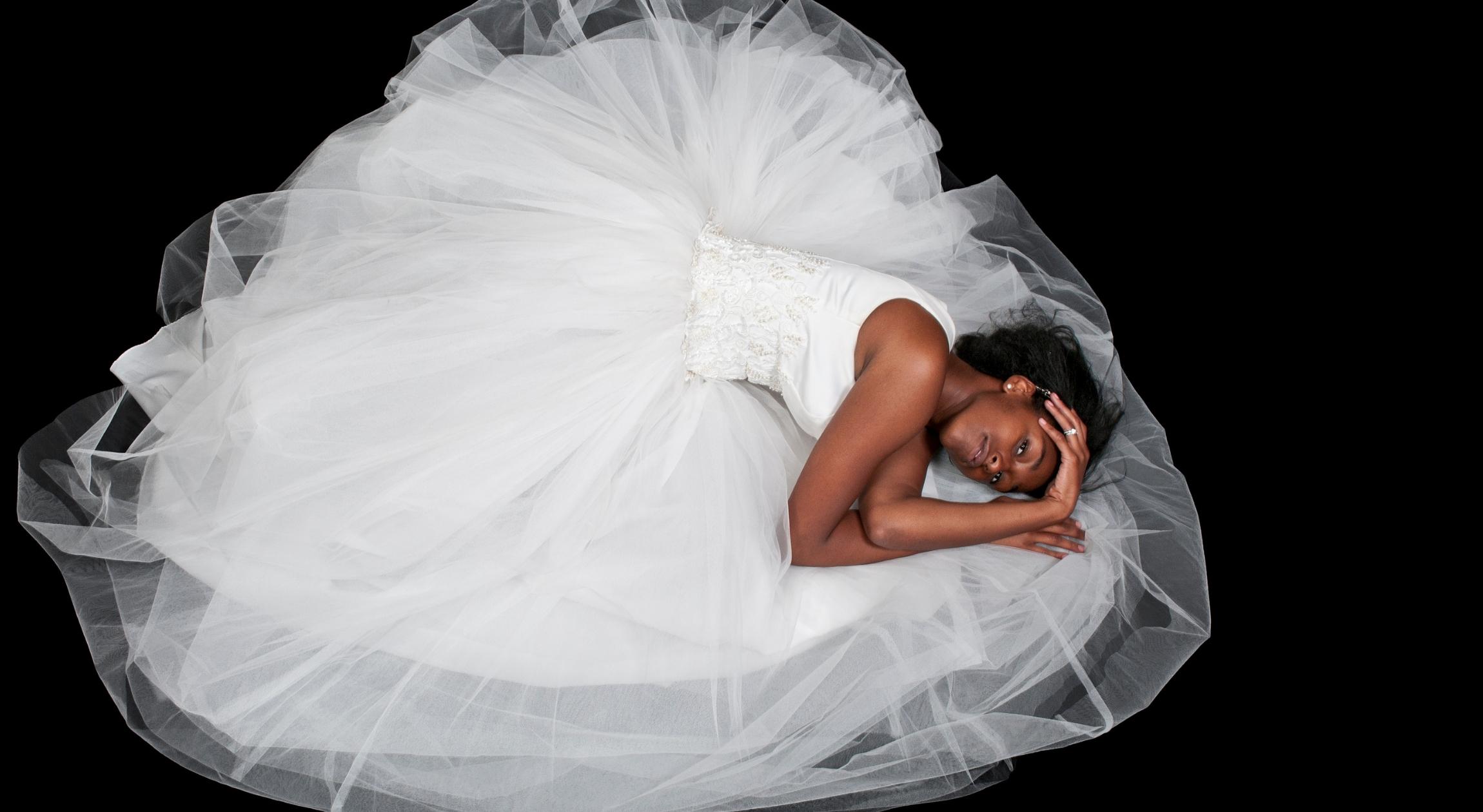 A Black woman in a white dress on the floor