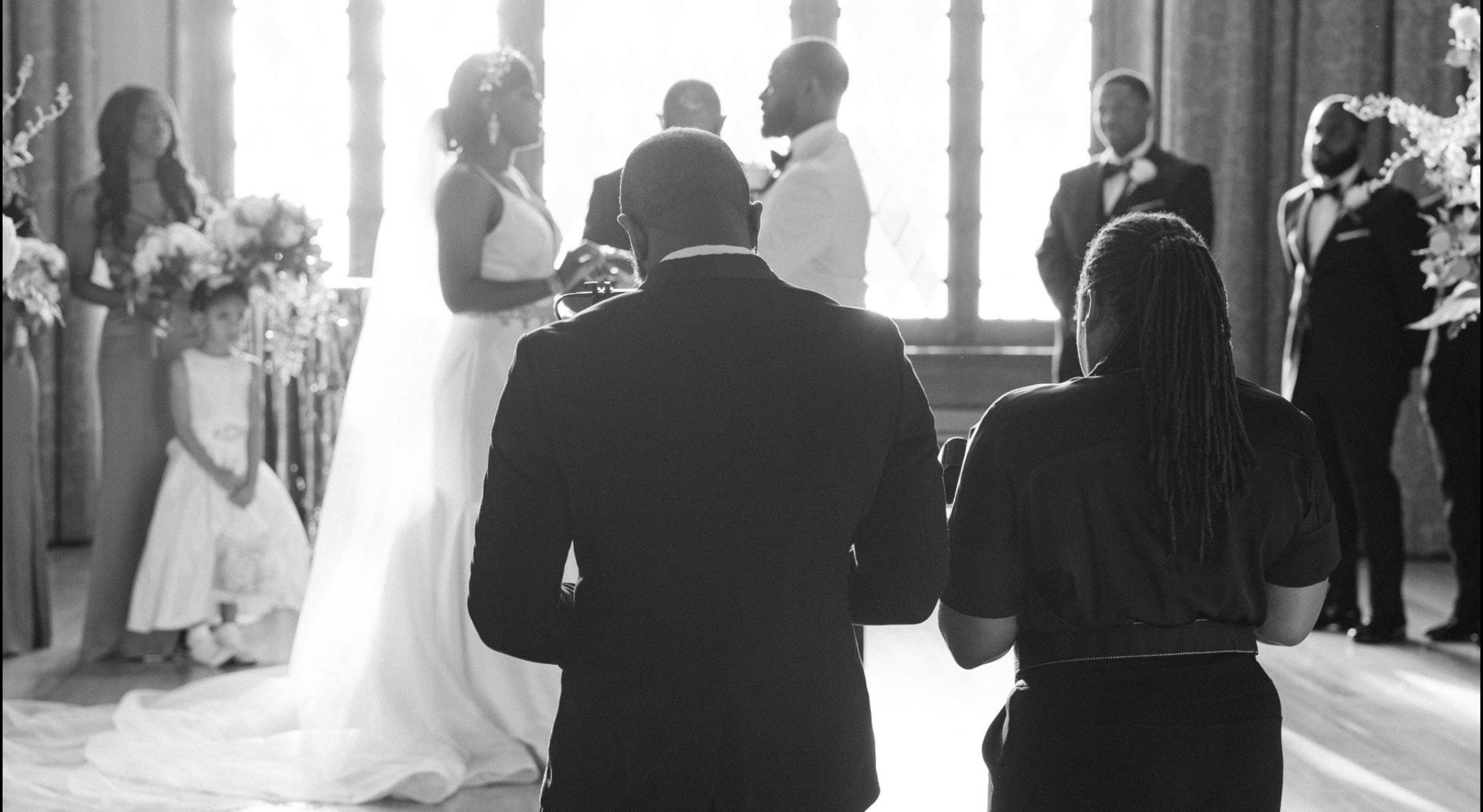 The back of a Black couple capturing the wedding of another Black couple