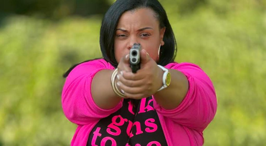 A Black woman holding a gun