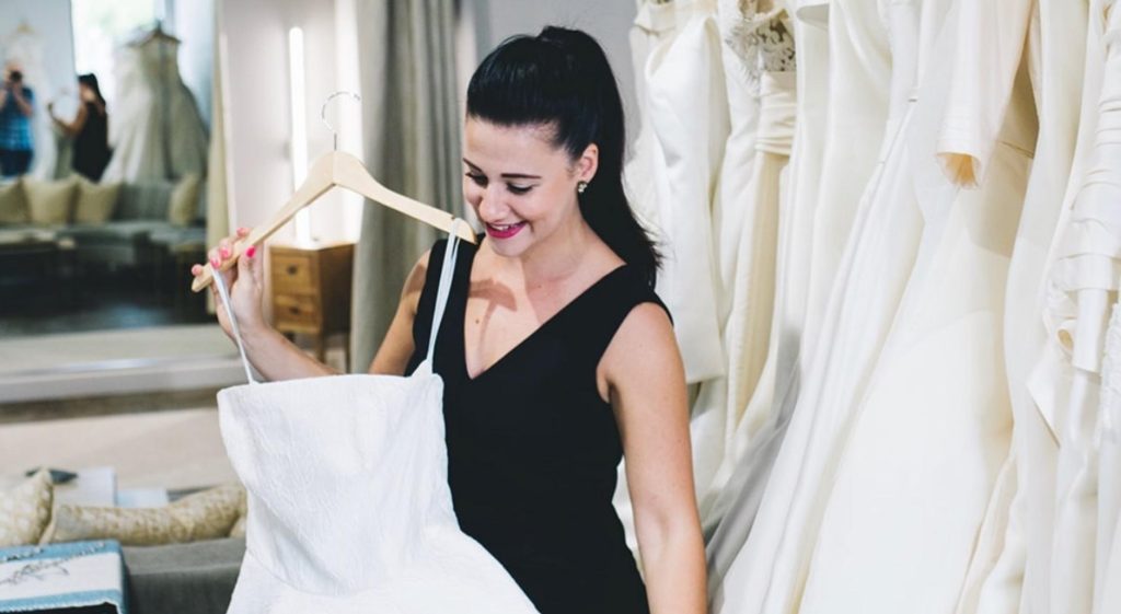 A Latinx woman holds a wedding dress