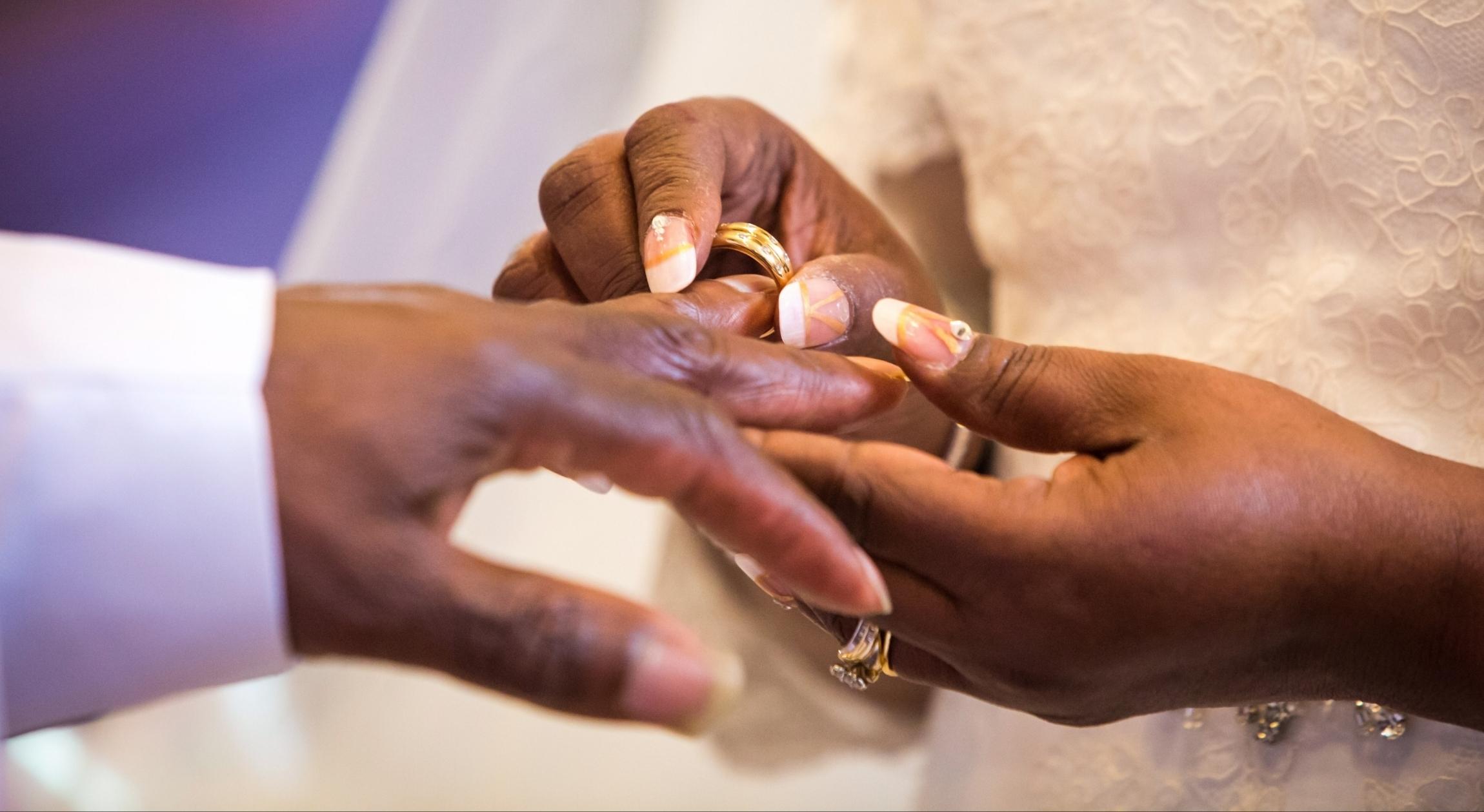 Black hands exchanging rings during a wedding