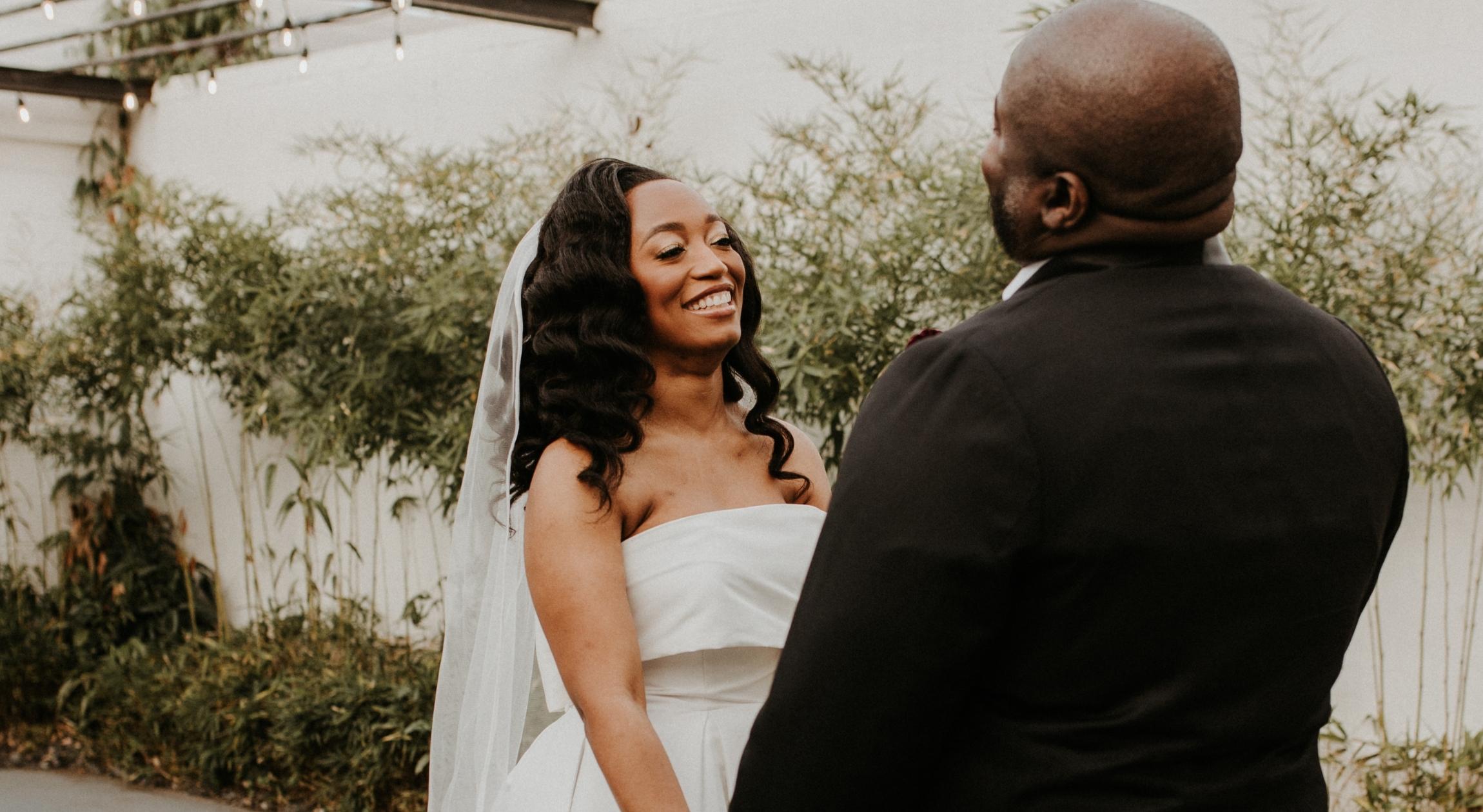 A Black bride smiling facing a Black groom