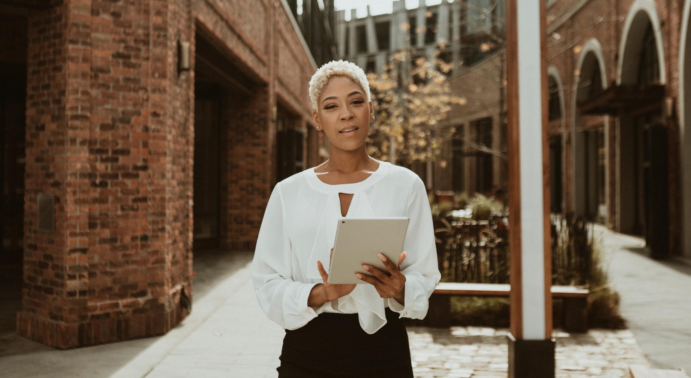 A Black woman with short blonde hair holds a clipboard