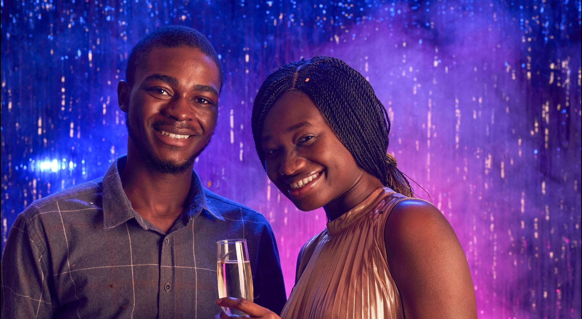 A Black couple standing in front of a purple blue background