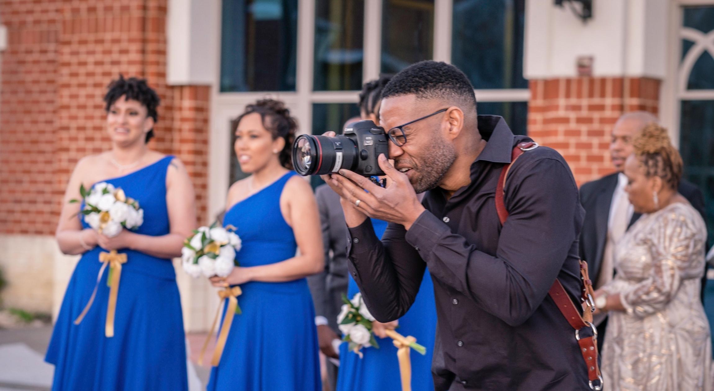 A Black photographer looks into a professional camera
