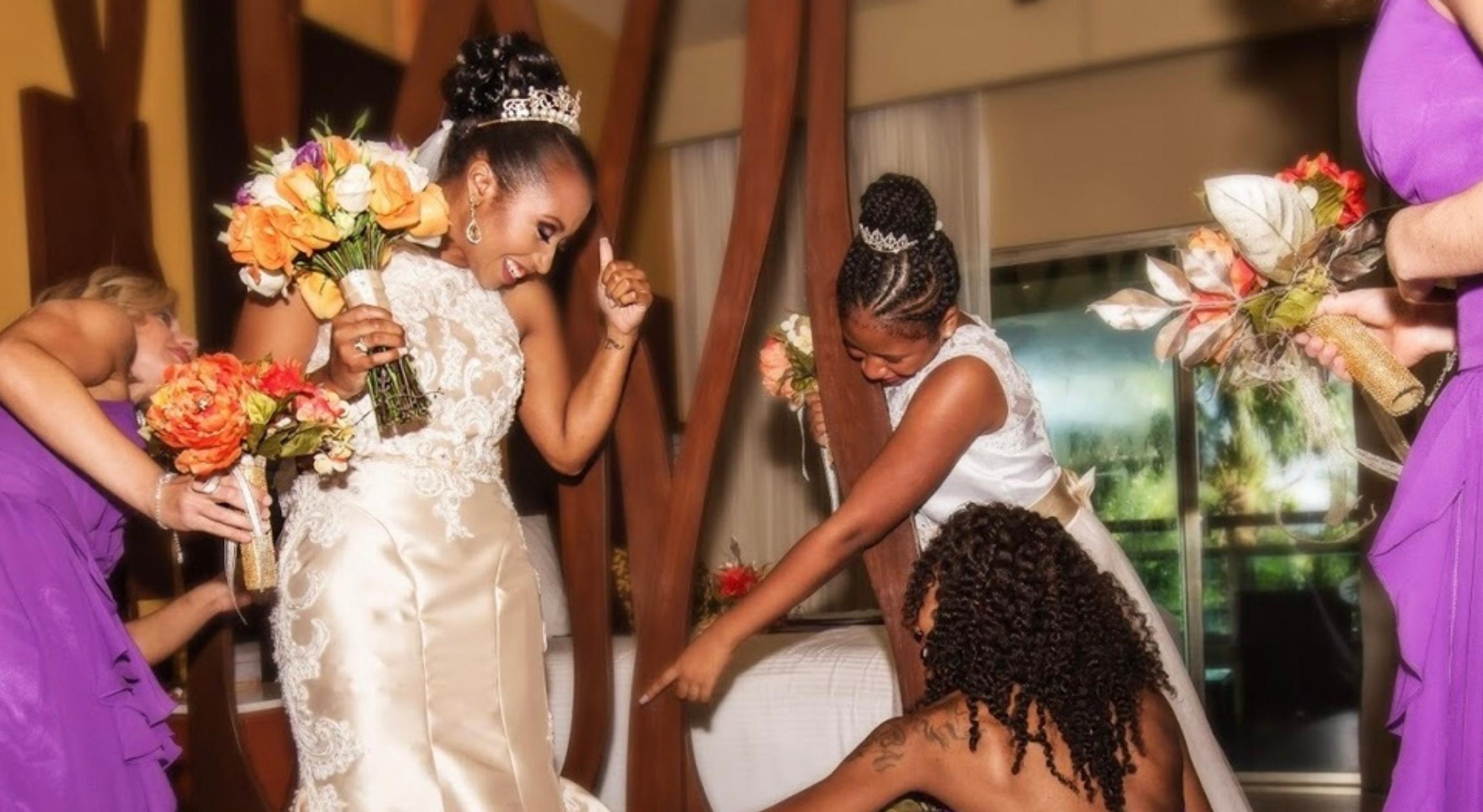 Several Black women helping a Black bride in her wedding dress