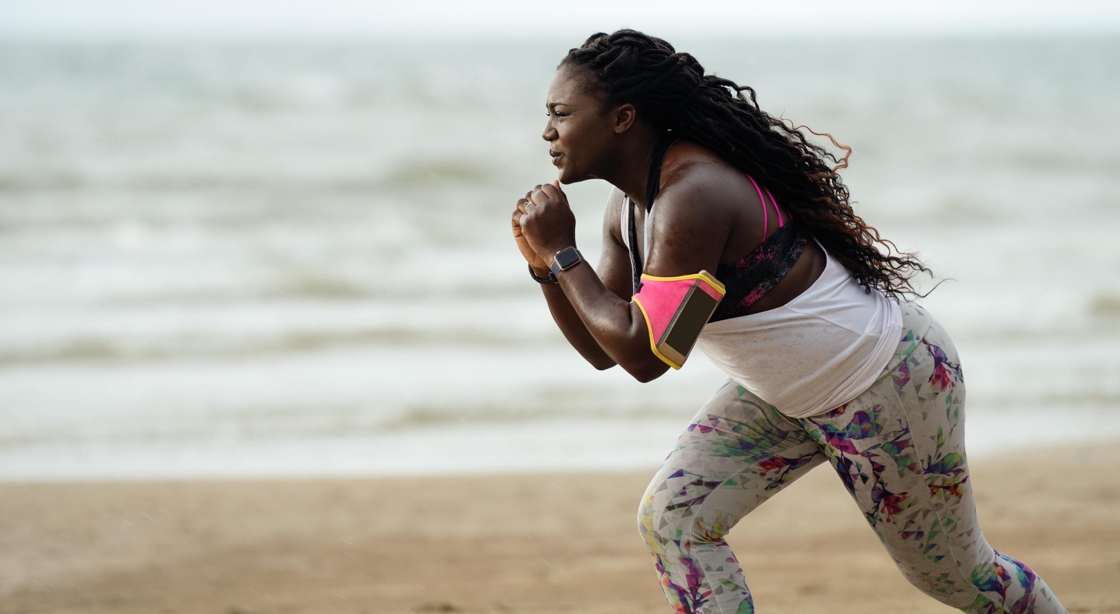 A Black woman in workout attire on the beach