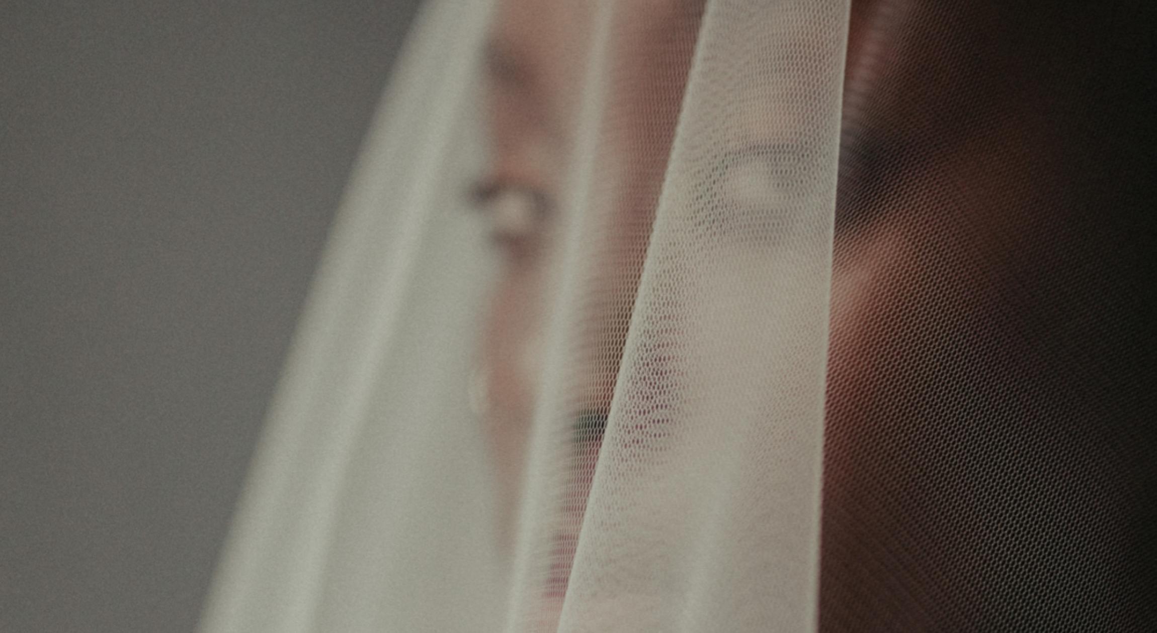 A Black bride looks through a veil