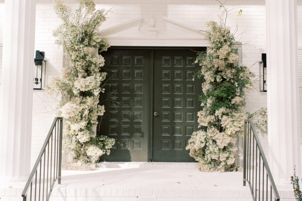 The door to a house surrounded by a floral stand