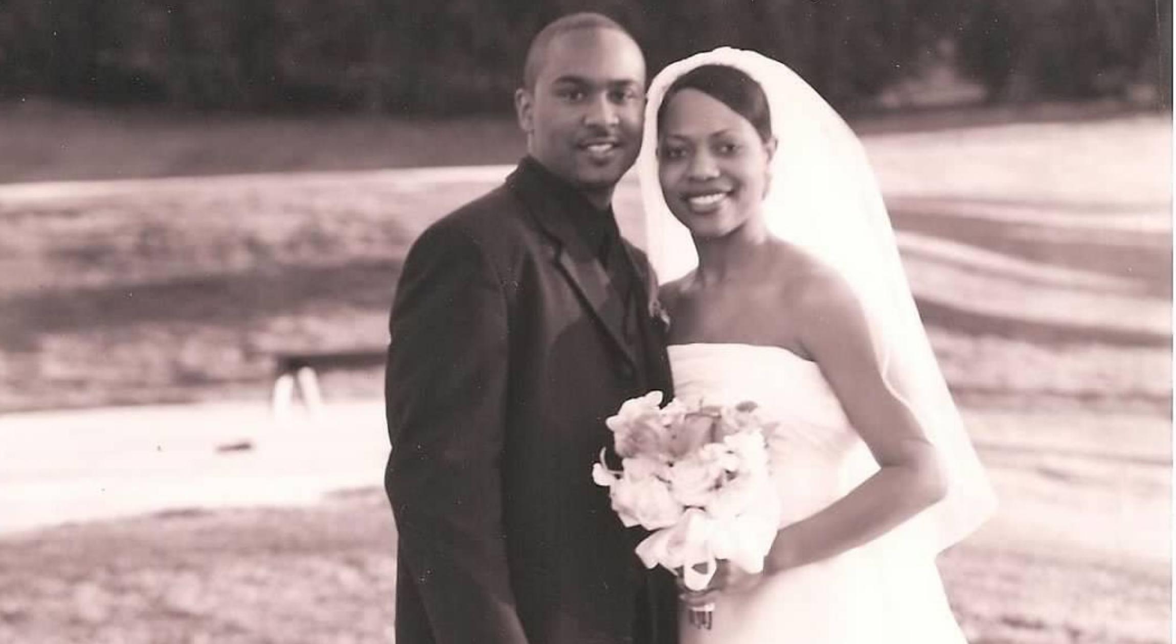 A Black newly married couple on a golf course smiles during their wedding