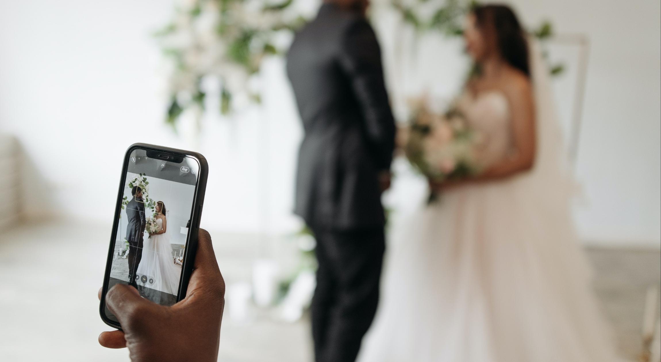 Someone holds a cell phone to capture a wedding
