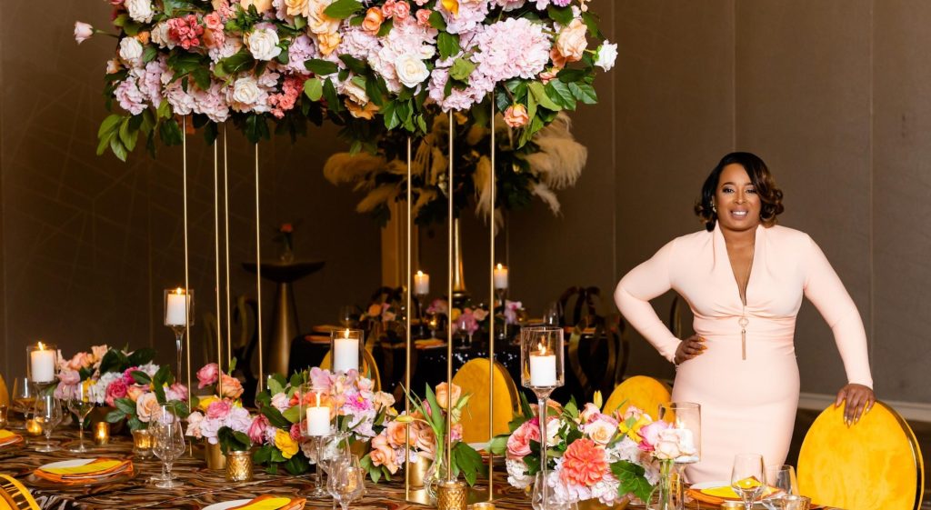 A Black woman in a pink dress standing at a decorated wedding table