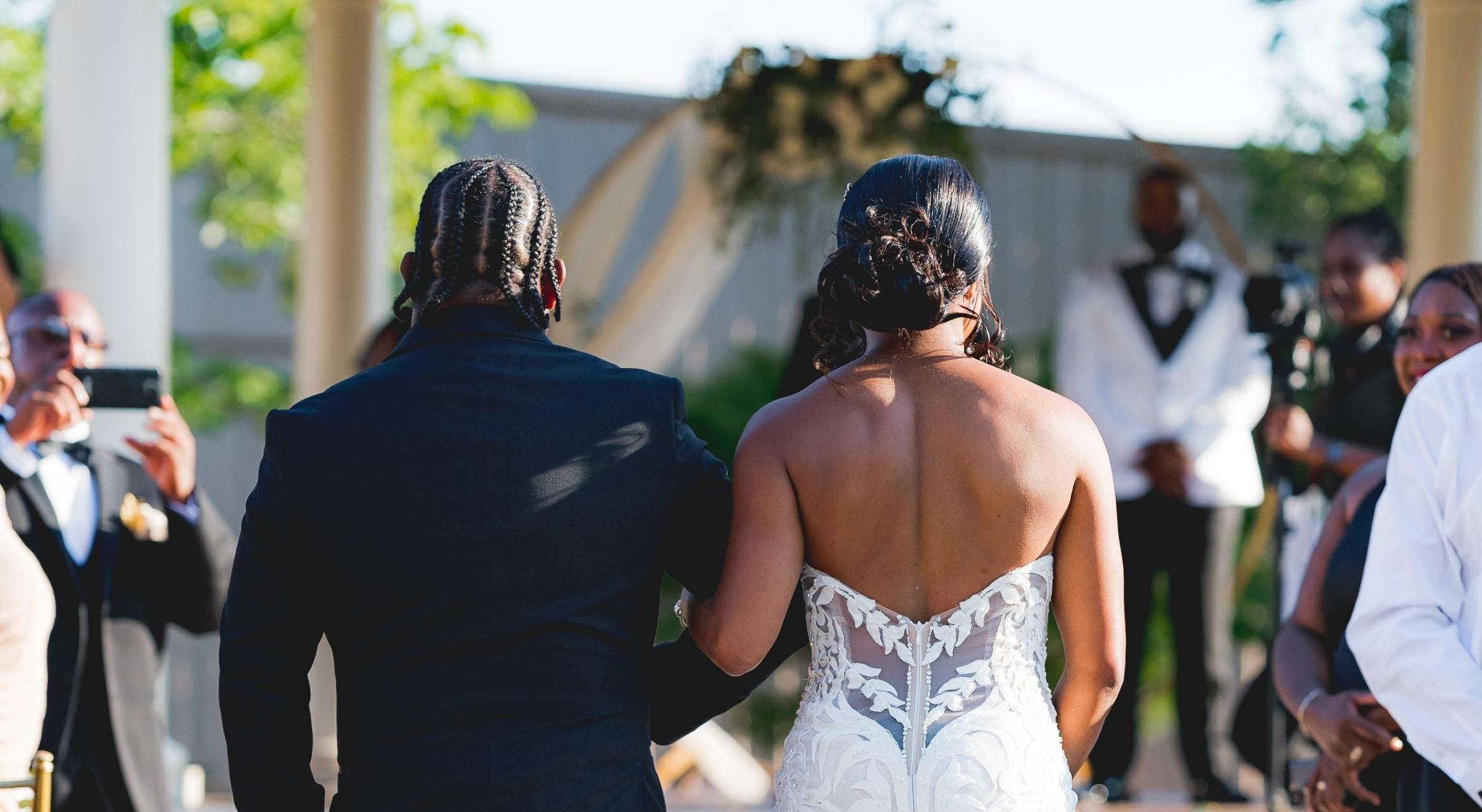 A Black father walks his daughter down the aisle