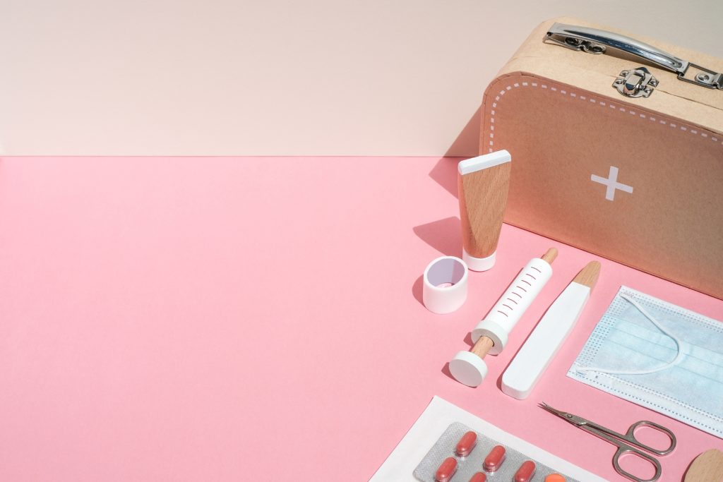 Pink and wooden items next to an emergency kit container