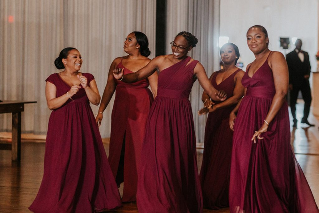 Bridesmaids in burgundy dresses dancing at a wedding reception