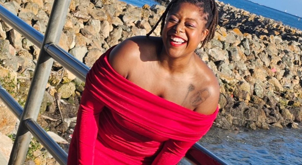 a person in a red dress smiling by the water