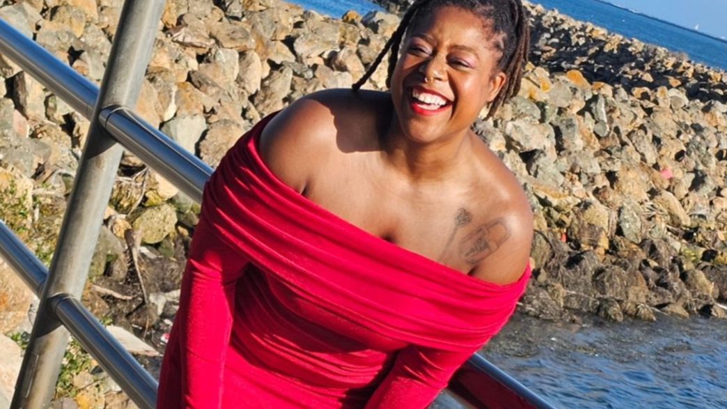 a person in a red dress smiling by the water