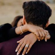 An engaged couple hugging in the middle of the field