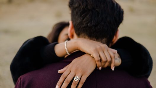 An engaged couple hugging in the middle of the field