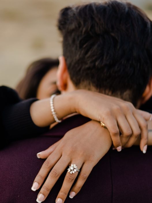 An engaged couple hugging in the middle of the field