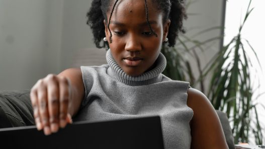 A person sitting on a couch looking at their laptop.