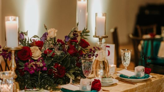 a table setting with red and gold flowers and candles