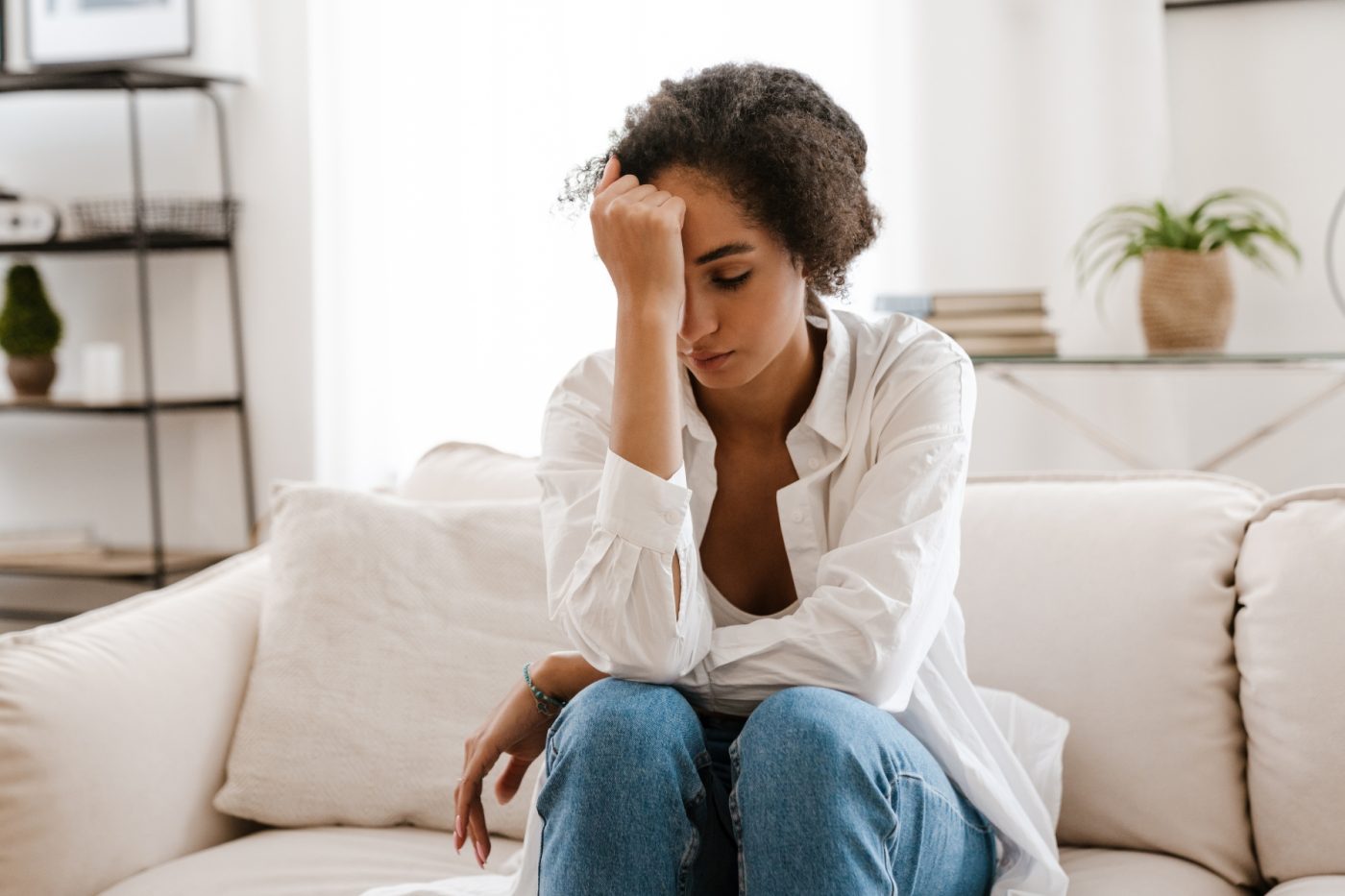 A person sitting on a couch with their head in their hands.