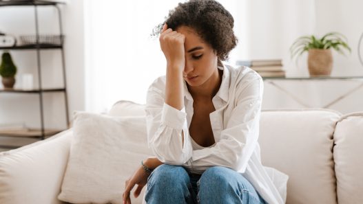 A person sitting on a couch with their head in their hands.