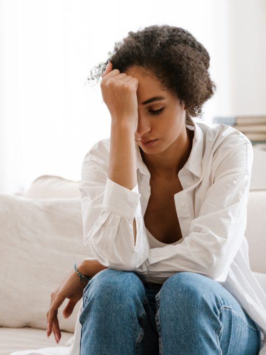 A person sitting on a couch with their head in their hands.
