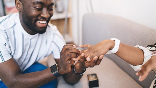 A person is putting a ring on their partner's finger.