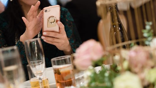 A wedding content creator taking a selfie with a cell phone at a wedding reception.