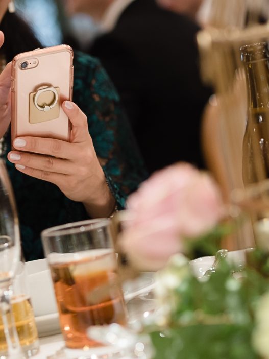 A wedding content creator taking a selfie with a cell phone at a wedding reception.