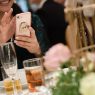 A wedding content creator taking a selfie with a cell phone at a wedding reception.