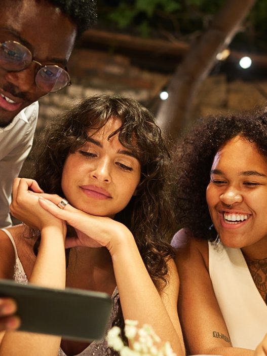 A wedding content creator vs. guest is at a table looking at a cell phone with the couple of honor.