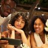 A wedding content creator vs. guest is at a table looking at a cell phone with the couple of honor.