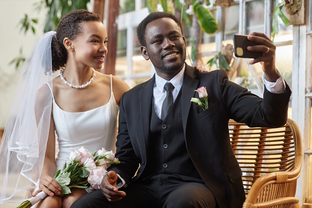 A Black couple taking a selfie at their wedding.