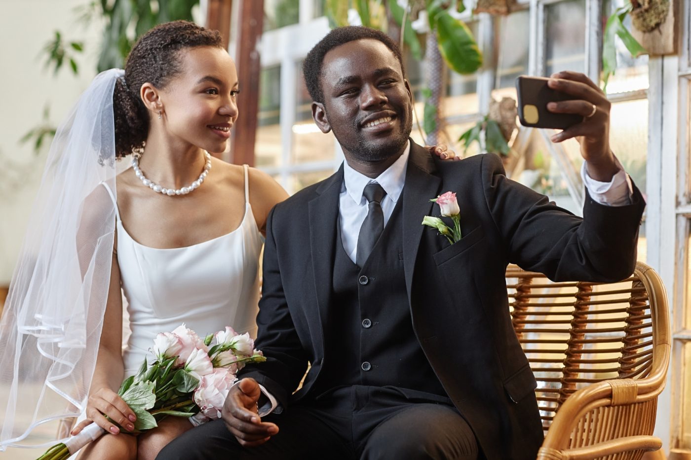 A Black couple taking a selfie at their wedding.