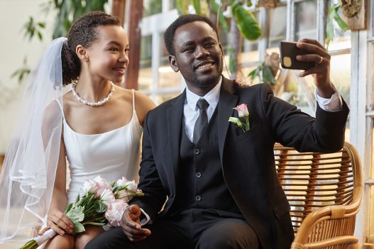 A Black couple taking a selfie at their wedding.