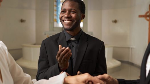 A wedding officiant stares at the couple with a smile during the ceremony