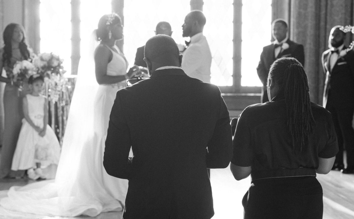 The back of a Black couple capturing the wedding of another Black couple
