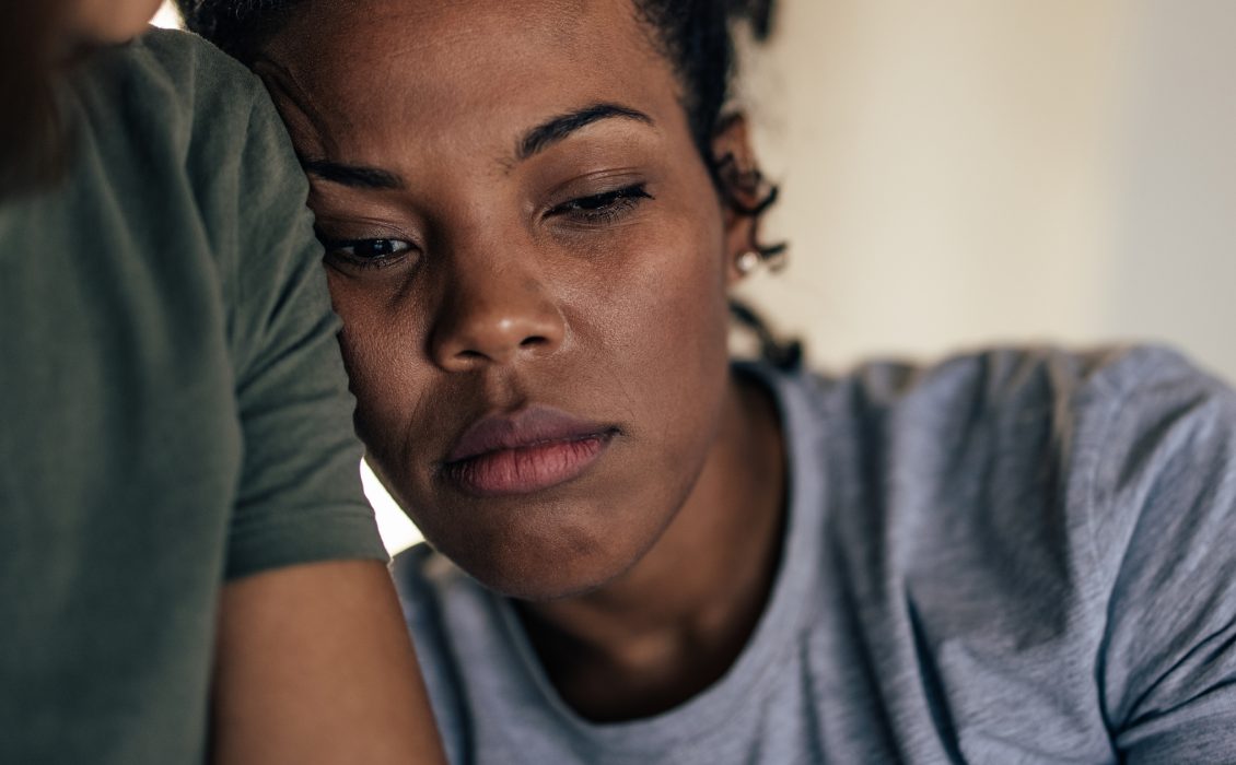 A sad African American woman leaning on the shoulder of someone
