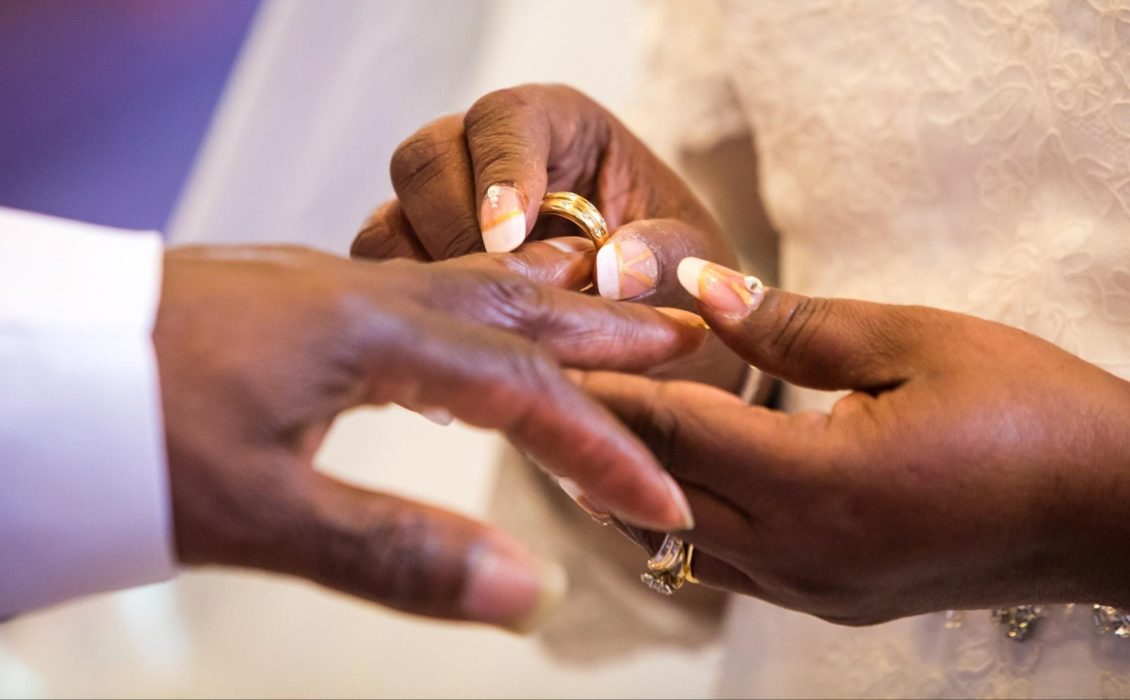 Black hands exchanging rings during a wedding