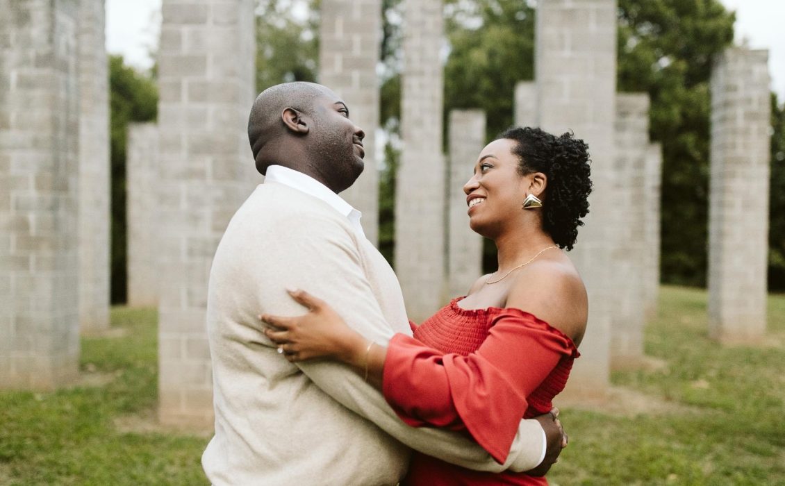 A Black couple in a park staring at each other as they embrace