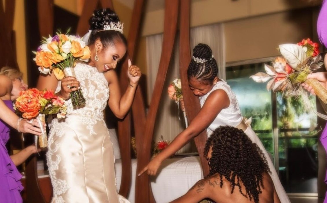 Several Black women helping a Black bride in her wedding dress