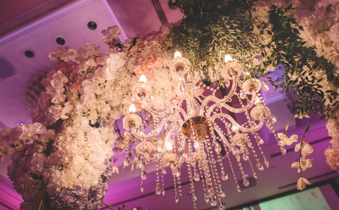 A chandelier handing on an installation with a lot of flowers