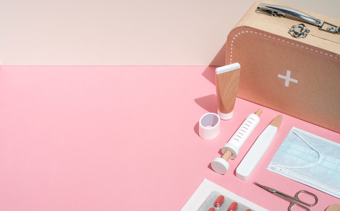 Pink and wooden items next to an emergency kit container
